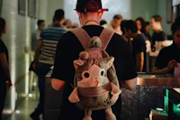 a man wearing a backpack with a stuffed cat on it